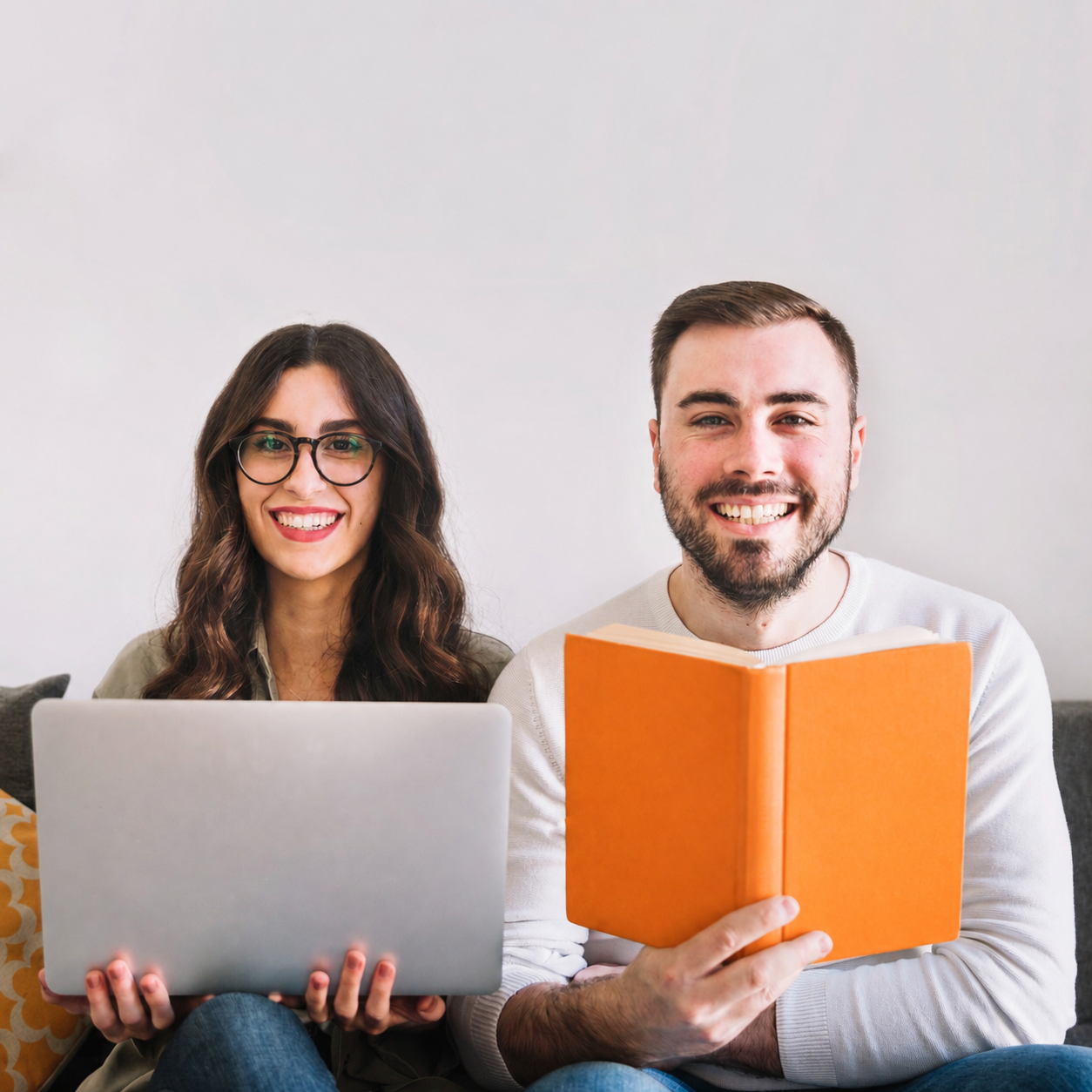Dos profesionales sonriendo: una con su notebook y otro con un libro, listos para formarse
